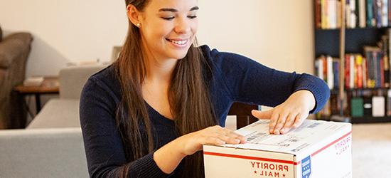Young woman labeling a USPS Priority Mail International package.